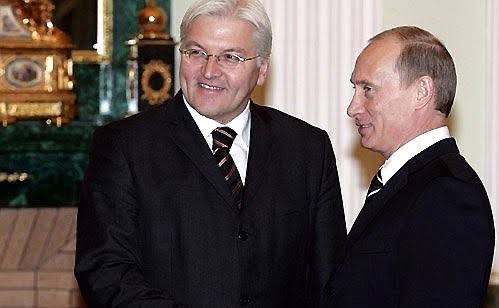 Frank-Walter Steinmeier, smiling, stands beside Vladimir Putin in an ornate room in the Kremlin