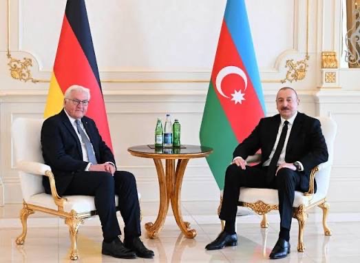 Frank-Walter Steinmeier and Ilham Aliyev seated in white armchairs before German and Azerbaijani flags