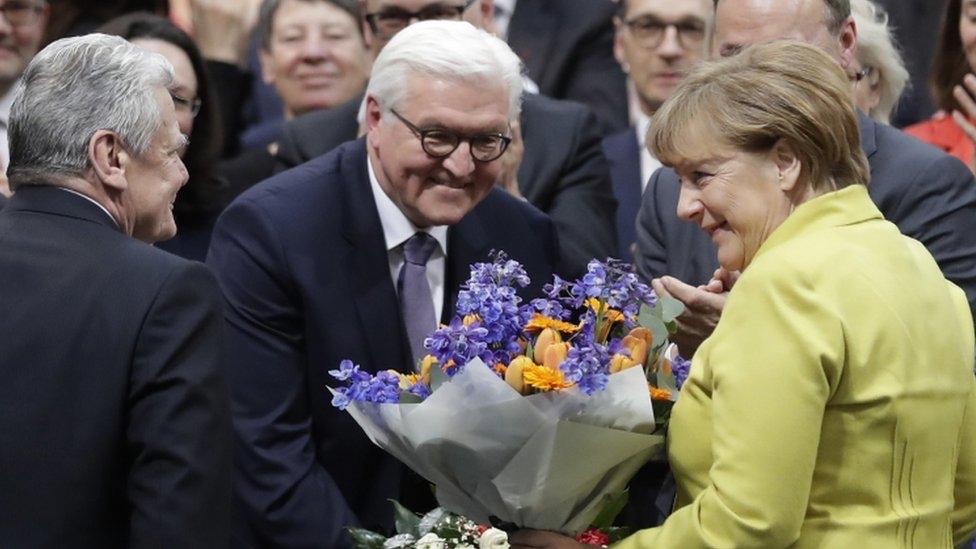 Steinmeier receives flowers from Angela Merkel after his election, as Joachim Gauck looks on