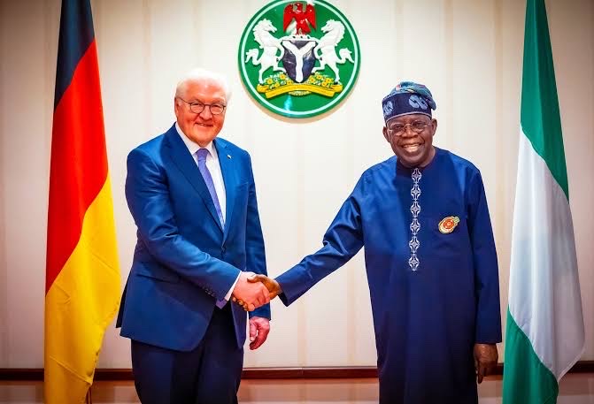 Frank-Walter Steinmeier shakes hands with Nigerian President Bola Tinubu in front of German and Nigerian flags and the Nigerian coat of arms