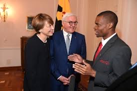Elke Büdenbender and Frank-Walter Steinmeier listening to a young man at a reception