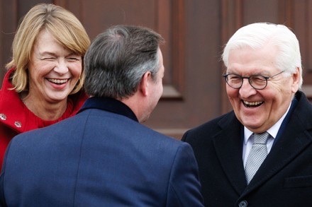 Elke Büdenbender and Frank-Walter Steinmeier laughing as they greet a guest outdoors